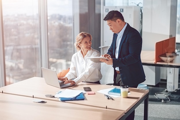 Two middle age confident business workers working together with smile on face using laptop