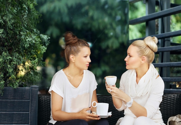 Two middleage woman using a smartphone and tablet outdoors