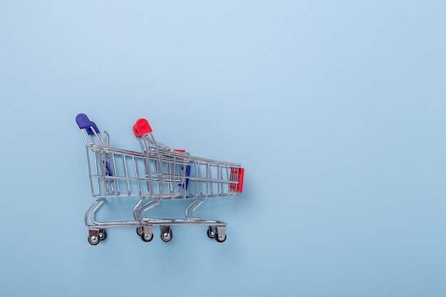 Two mini shopping carts on blue background Top view Copy space - Image