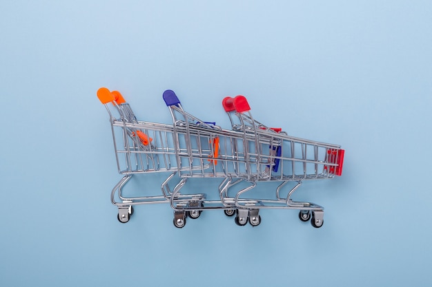 Two mini shopping carts on blue background Top view Copy space - Image