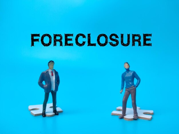 The two miniature people with the word FORECLOSURE on blue background