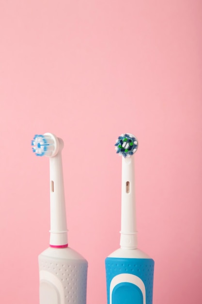 Two Modern electric toothbrushes on pink pastel background Top view Teeth care Minimalism