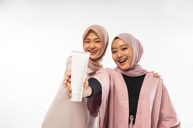 Two muslim beauty friend holding a tube cosmetic product for skincare