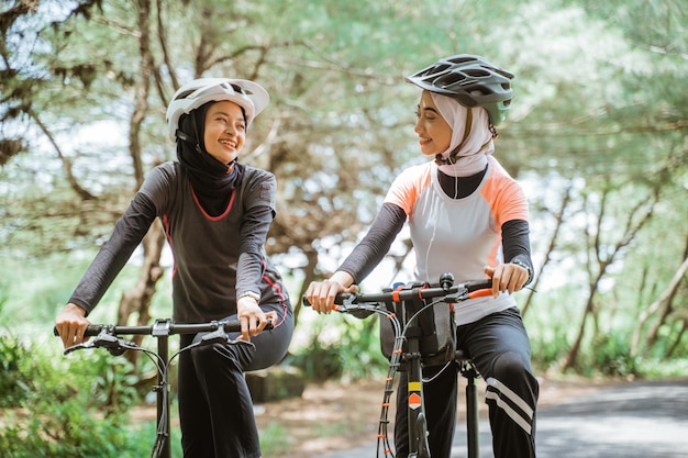 Two muslim women in sportswear and cycling helmets