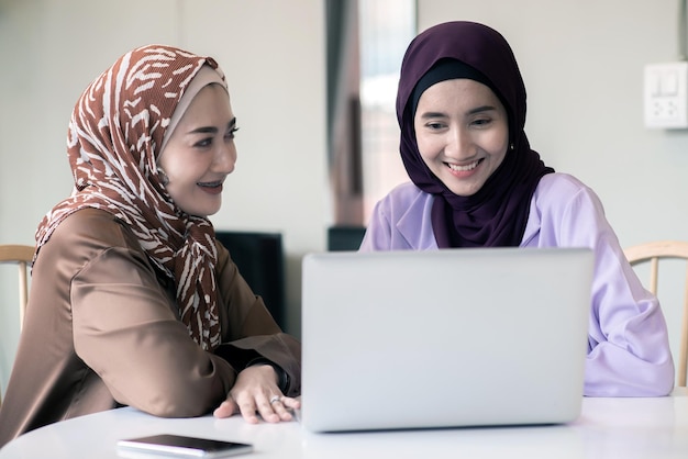 Two Muslim women using laptop for explaining business information in the room