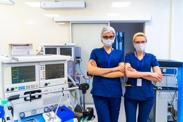 Two nurses standing in operating medical room in hospital Women in medical masks and scrubs Standing crosshands