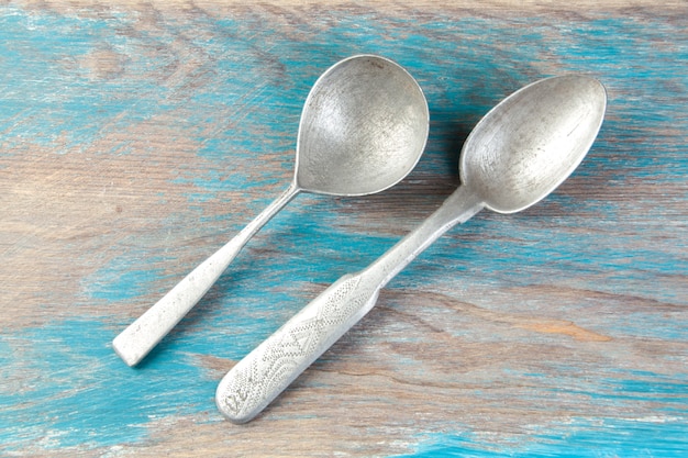 Two old aluminum spoons on blue wooden background. Copy space for text, food photography props.