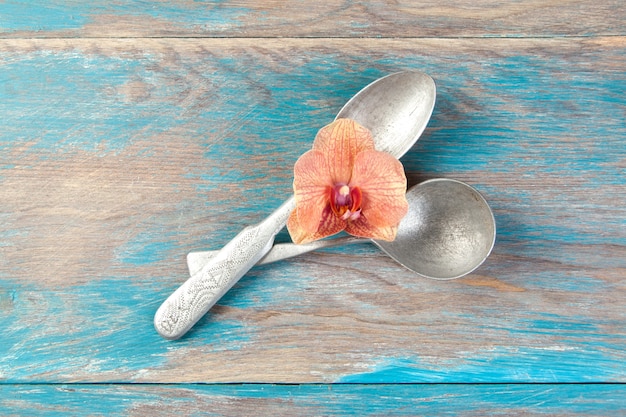 Two old aluminum spoons on blue wooden background. Copy space for text, food photography props.