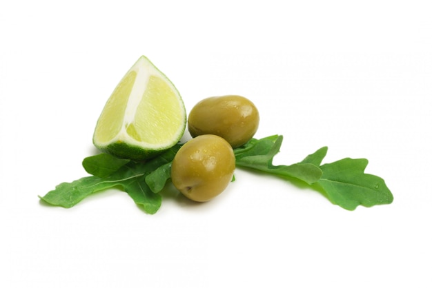 Two olives, piece of lemon and leaves of arugula isolated on white background.