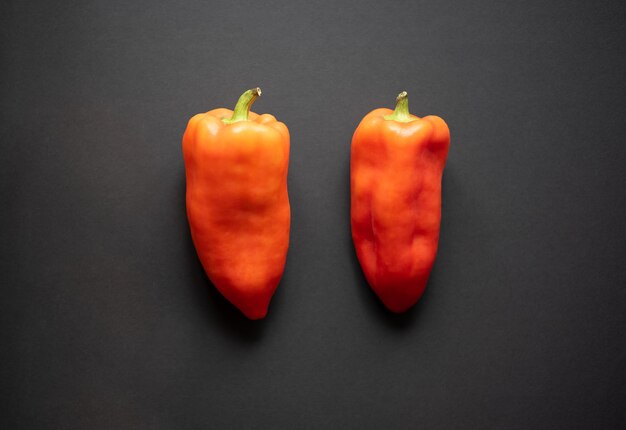 two orange bell peppers on a black background top view flat lay