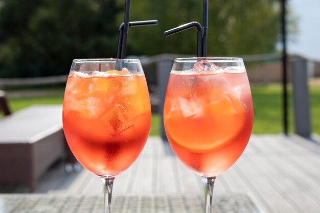 two orange cocktails aperol on a table by the beach in summer on a sunny day