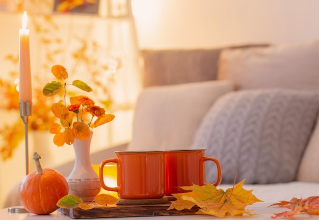 Two orange cups with hot drink in autumnal light interior