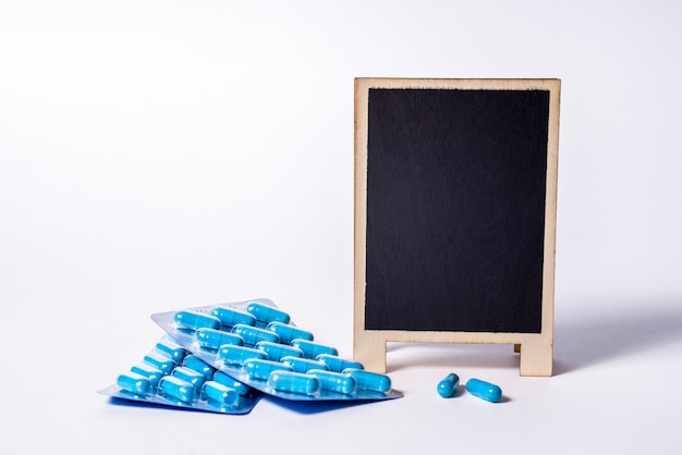 Two packages of blue capsules and a chalkboard  with space for text. Pills for men's health and sexual energy