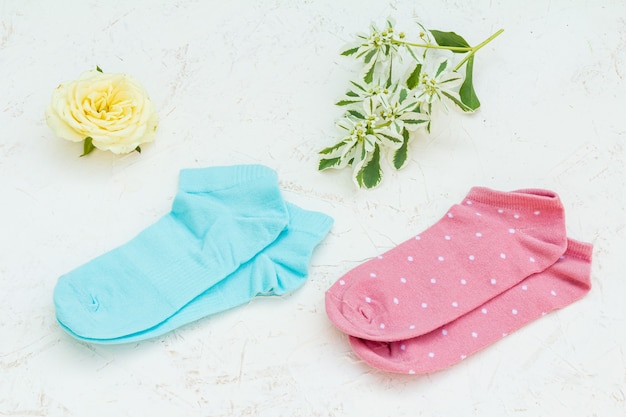 Two pair of women's socks and a bud of rose on the white structured background, Top view.