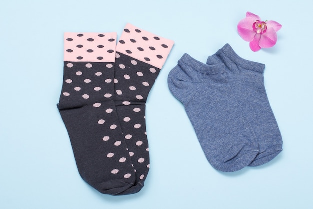 Two pair of women socks with orchid flower on a blue background, Top view.