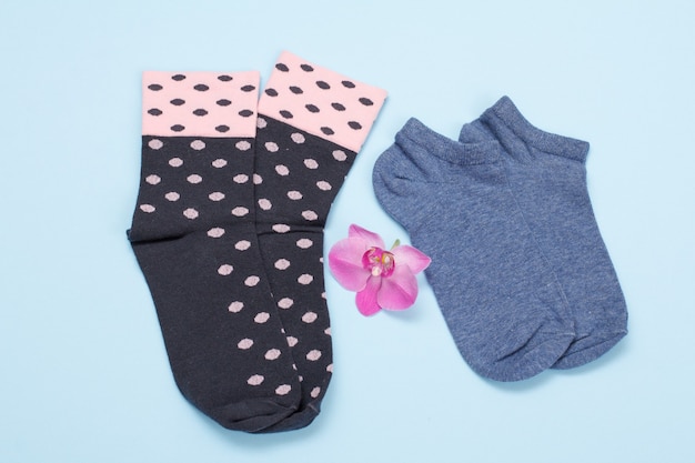 Two pair of women socks with orchid flower on a blue background, Top view.