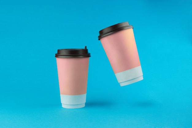 Two paper coffee cups on a blue background