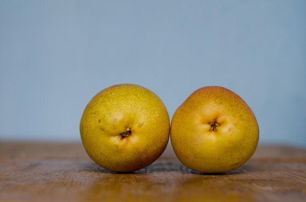 two pears standing on a wooden table and blurred cyan background