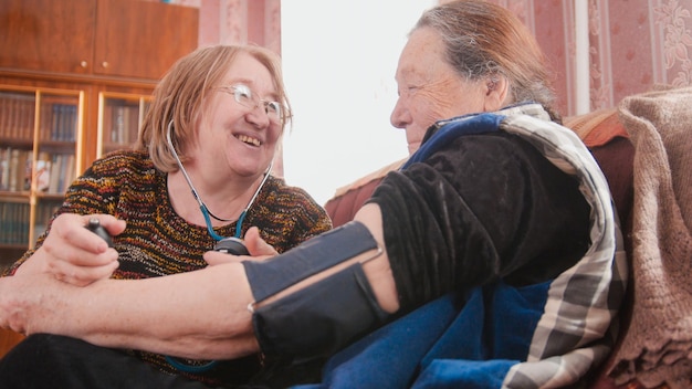 Two pensioners - senior ladies have fun - checking health state with manometer - measures pressure, pensioners healthcare, close up