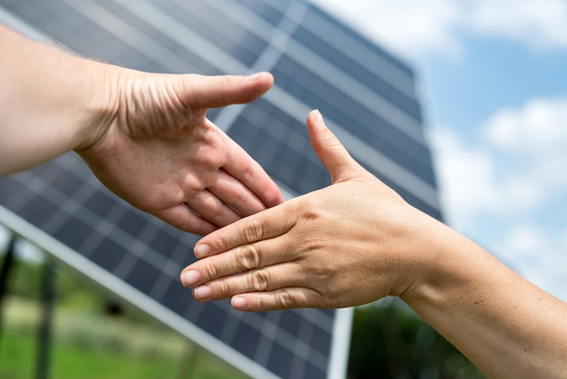 Two people handshake successful cooperation against solar farm background