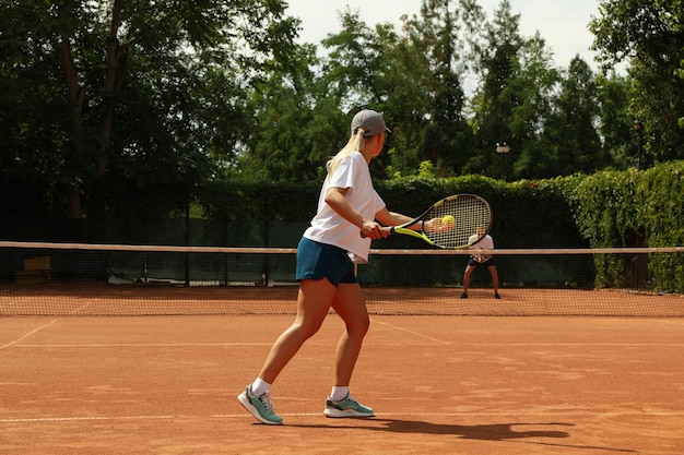 Two people playing tennis on clay court