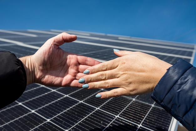 Two people shaking hands against a solar panel after signing a renewable energy deal