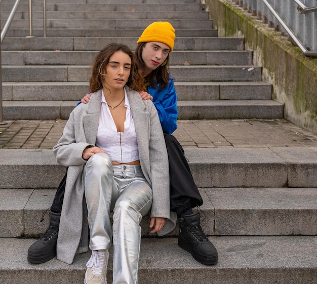 Photo two people sit on the steps one of them has a yellow hat on