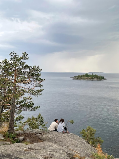 Two people sitting on a cliff overlooking the lake