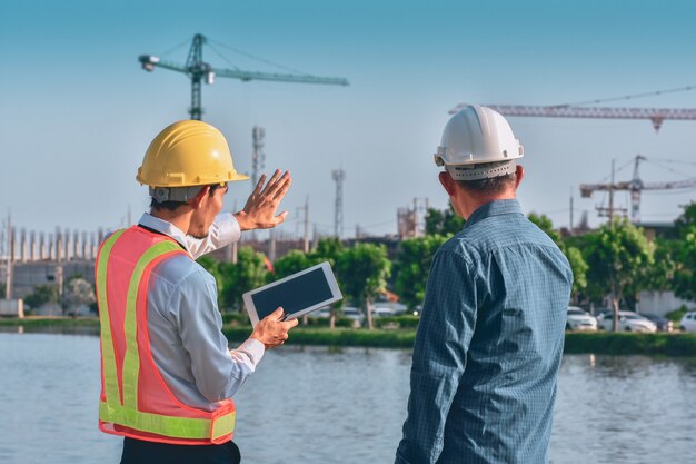 Two people worker Engineer talking discussion by tablet on site building real estate construction