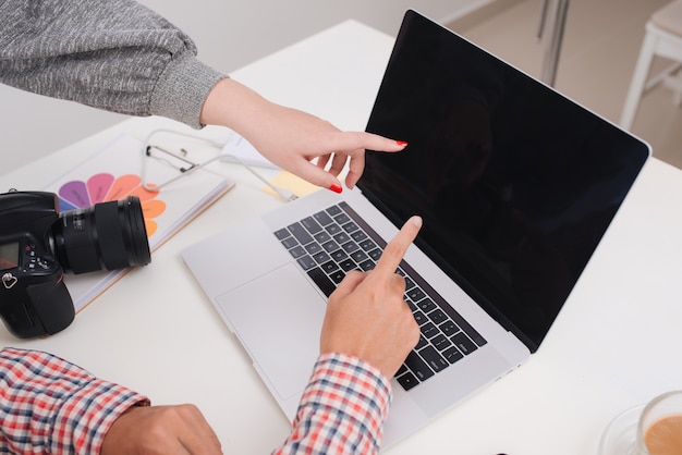 Two photographers with camera and laptop computer working in office