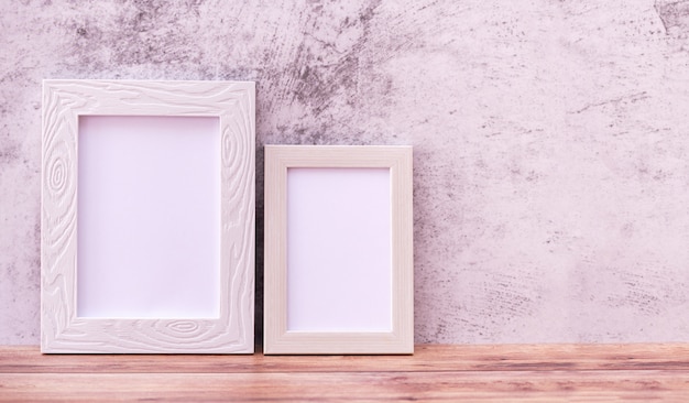 Two Picture frame on wall and wooden table.