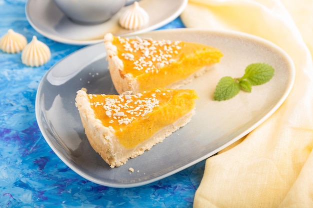 Two pieces of traditional american pumpkin pie with cup of coffee on a blue concrete background side view selective focus