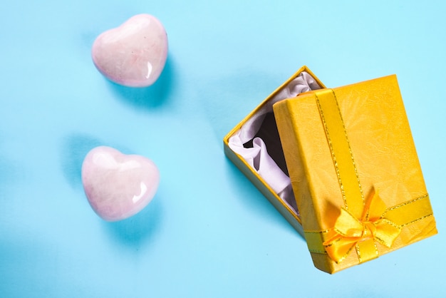 two pink hearts and yellow gift box on a blue background. valentines day or romance concept.