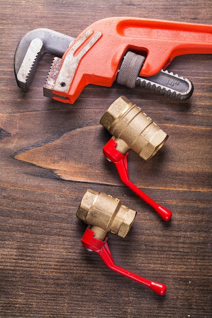 Two plumbers fixtures and monkey wrench on vintage wooden board