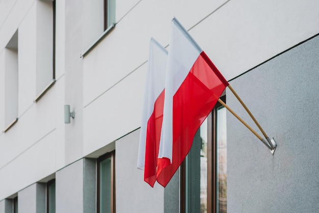 Two Polish flags hanging on the facade of white governmental building Nation Europe Embassy Communication Power Control