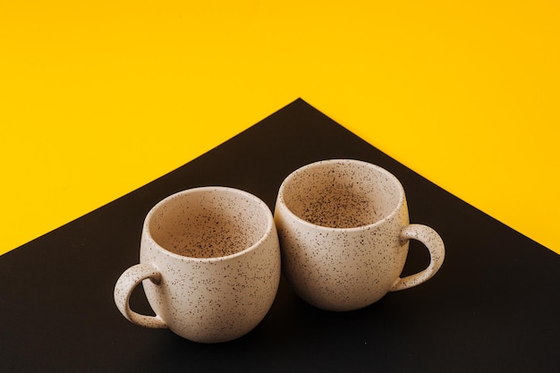 Two porcelain empty cups on a black and yellow background copy space