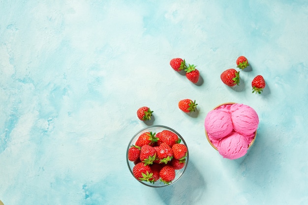 Two portions strawberry ice cream in paper cup on mint colors background, top view