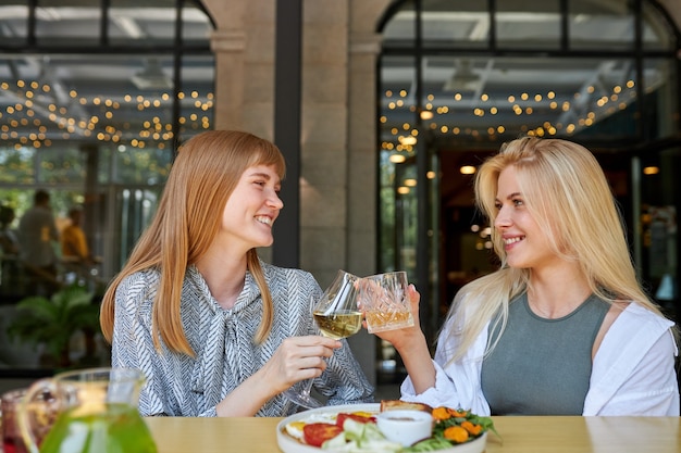 Two positive caucasian women enjoy spending time together in restaurant