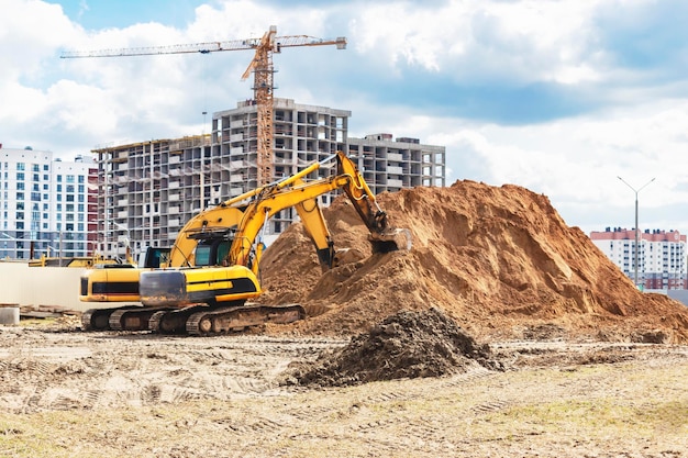 Two powerful excavators work at the same time on a construction site sunny blue sky in the background Construction equipment for earthworks