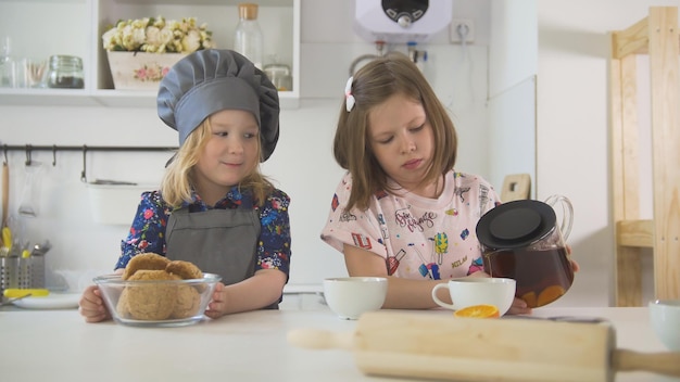 Two preschool girls bakers drinks tea close up