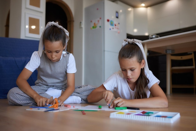 Two preschoolers playing with colorful plasticine and having fun focus on the girl on the right