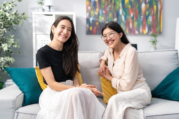 Two pretty brunette friends hang out on the sofa in a modern apartment roommates students joke tell