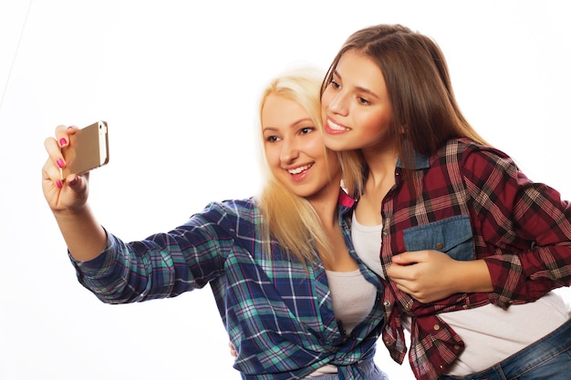 Two pretty hipster girls taking selfie. Isolated on white background.