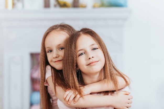 Two pretty little girls sisters happily cuddle and laugh