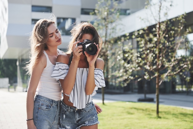 Two pretty pretty friends of the girl with the camera take photos together and walk in the city.