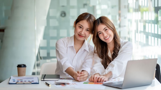 Two pretty Young Asian businesswoman or intern who sitting smile happily in the office Looking at camera