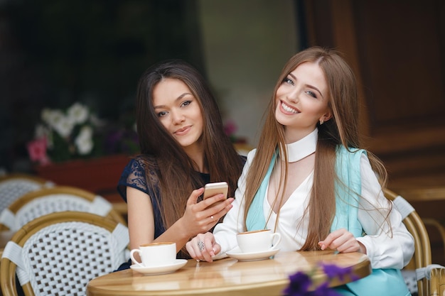 two pretty young women in cafe with coffee and phone