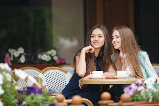 two pretty young women in cafe with coffee and phone