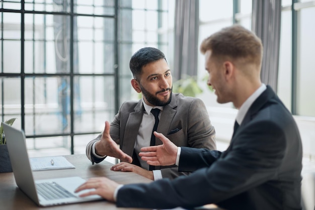 Two professional businessmen discussing and using desktop computer in office