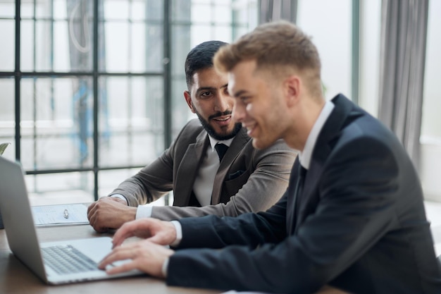 Two professional businessmen discussing and using desktop computer in office